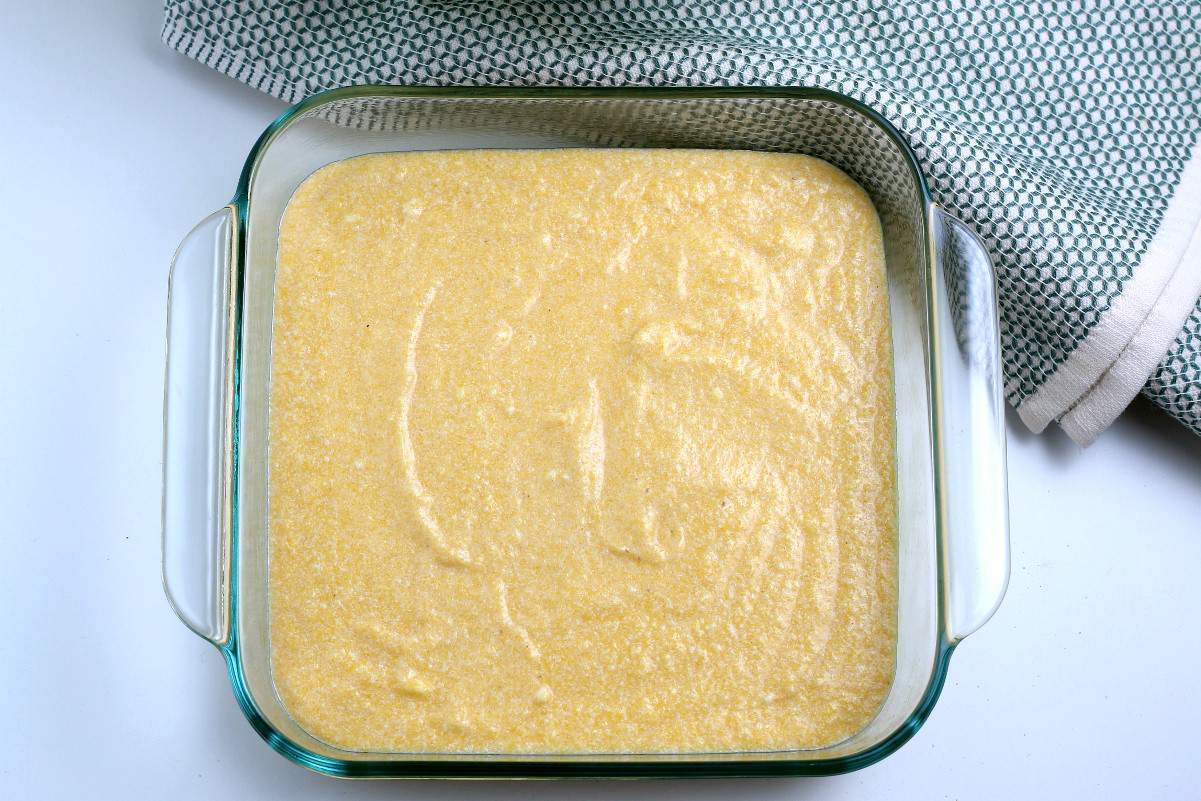 Overhead view of raw cornbread batter in a square baking dish.