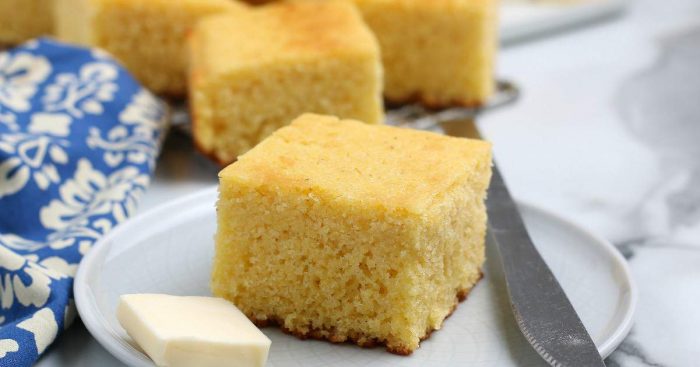 Wide photo of a piece of cornbread with more stacked behind.