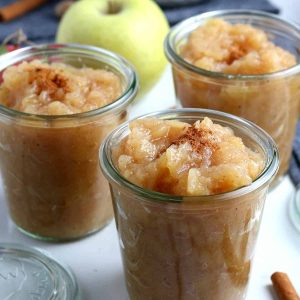 Three clear jars full of applesauce.