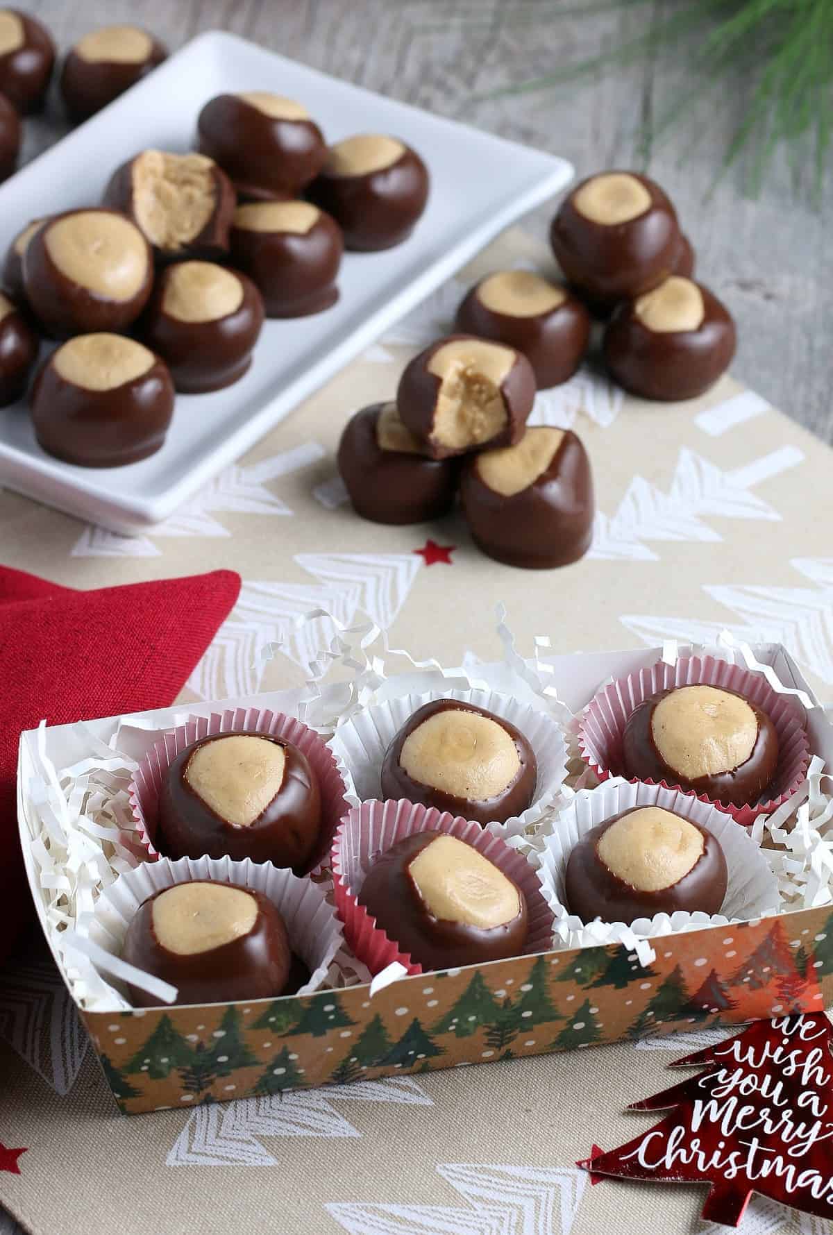 Box full of vegan buckeye candy in paper cups with red and white decoration.