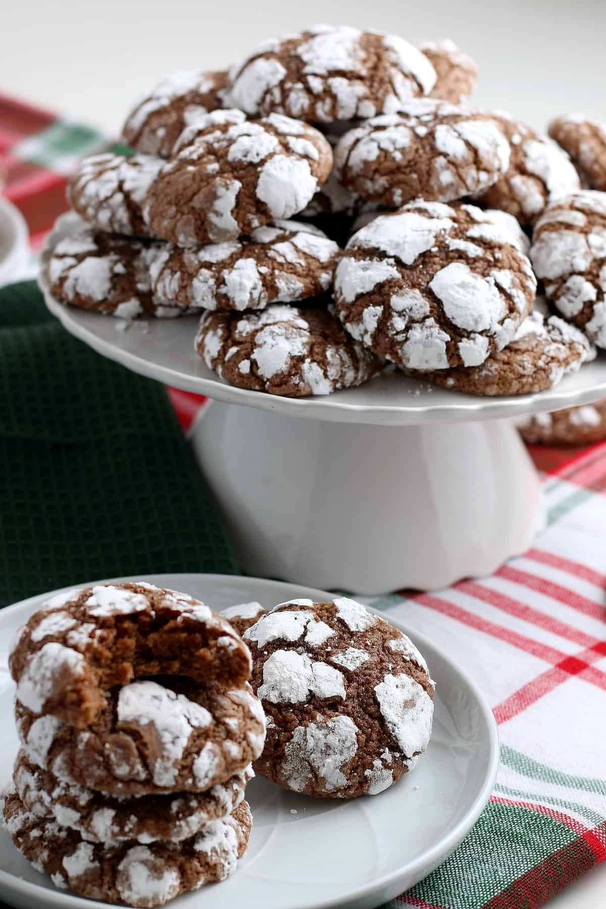 A compote is stacked with a pile of vegan crinkle cookies and more in front.