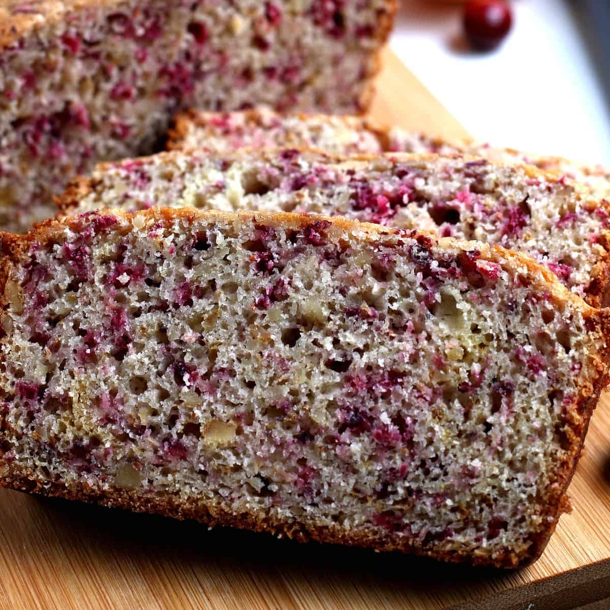 Close up slices of cranberry orange bread on a cutting board.