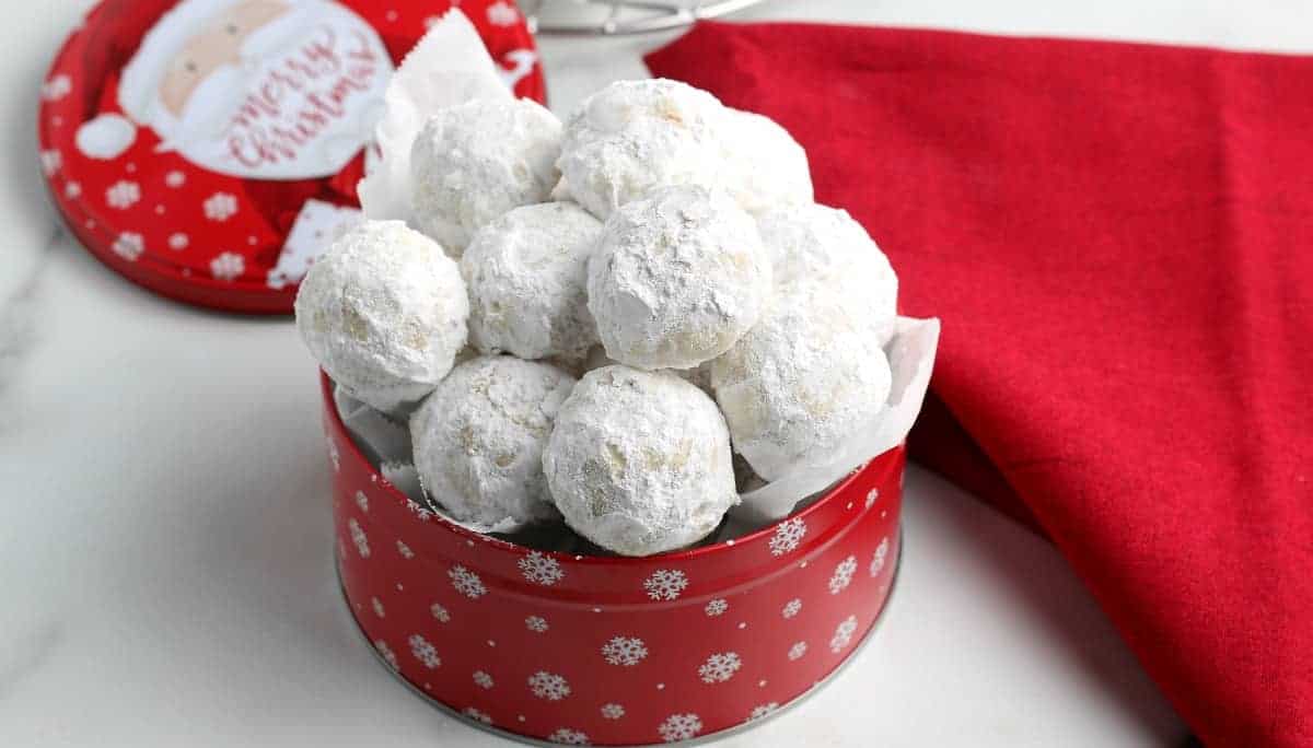 White round treats are filling a red Christmas tin.