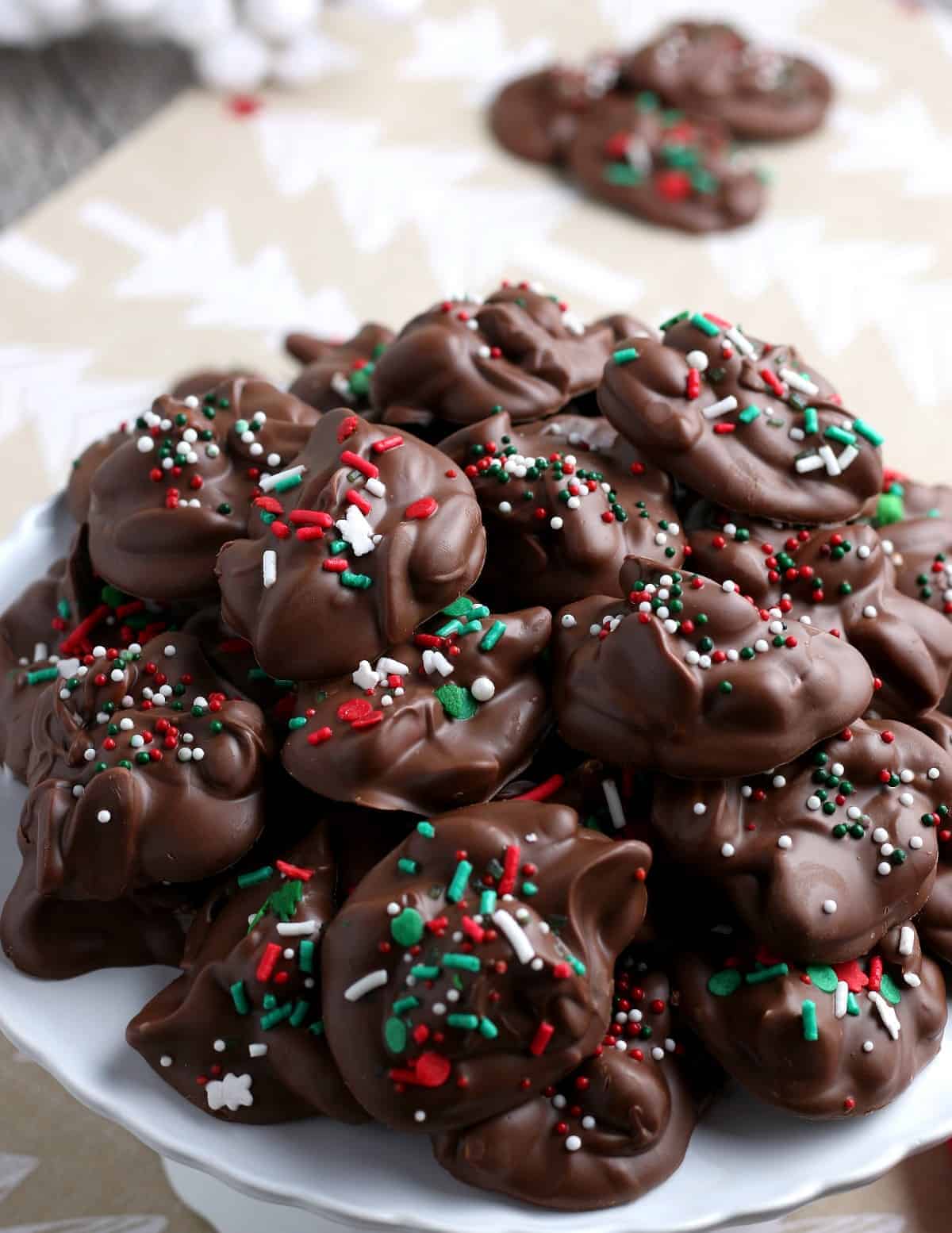 Huge pile of chocolate candies sprinkled with red, white and green sprinkles.