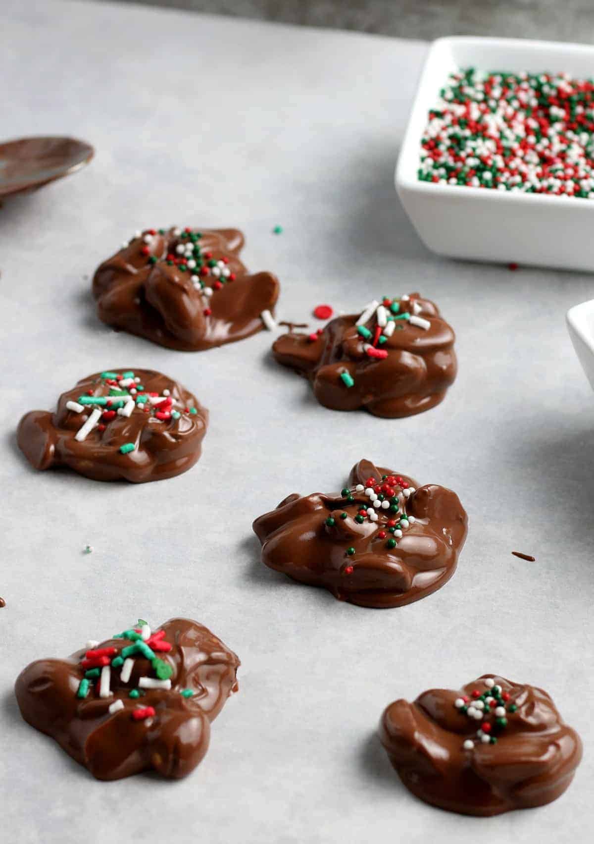 Dollops of chocolate candies are spread out on parchment paper.