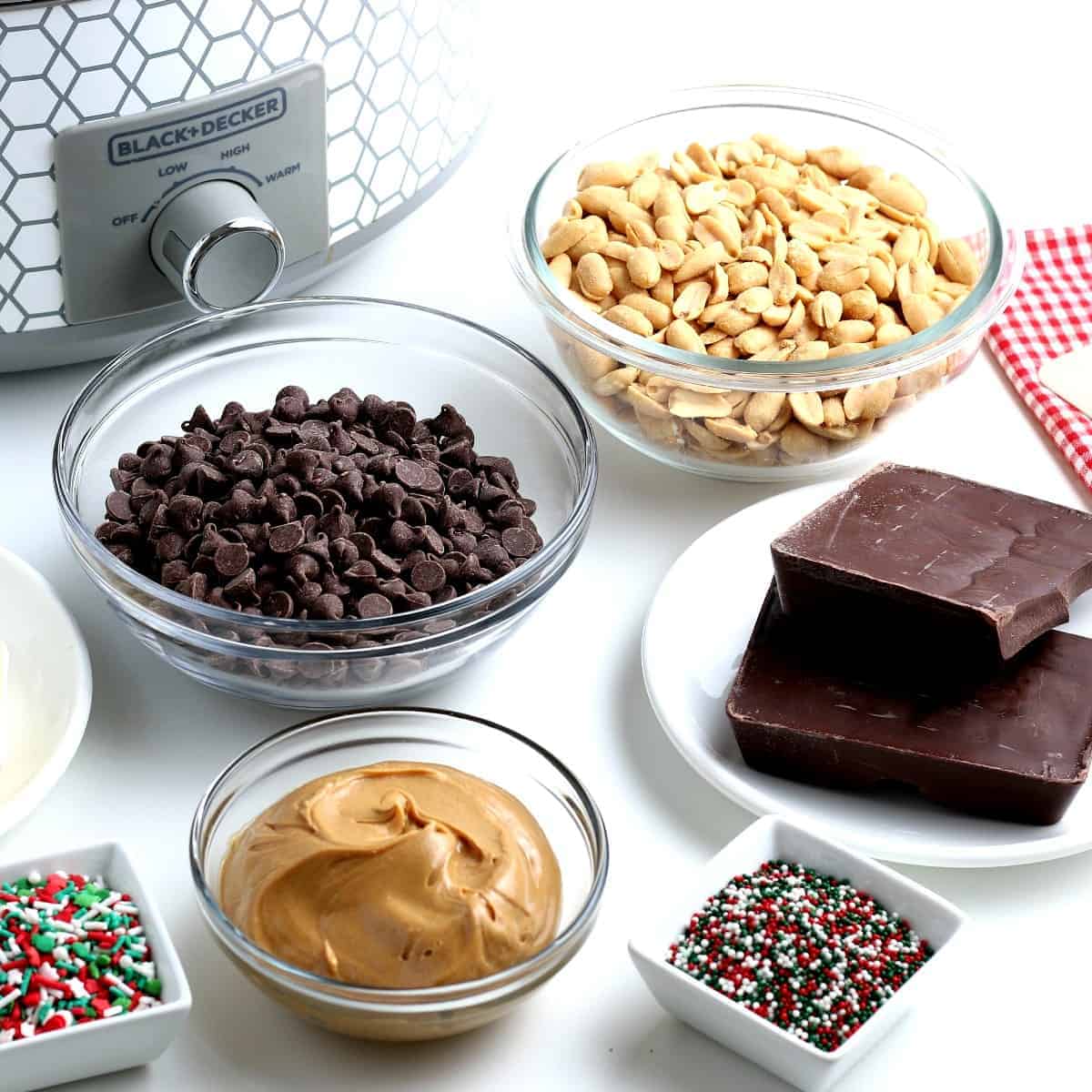 The five ingredients are sitting in front of a crock pot along with sprinkles.