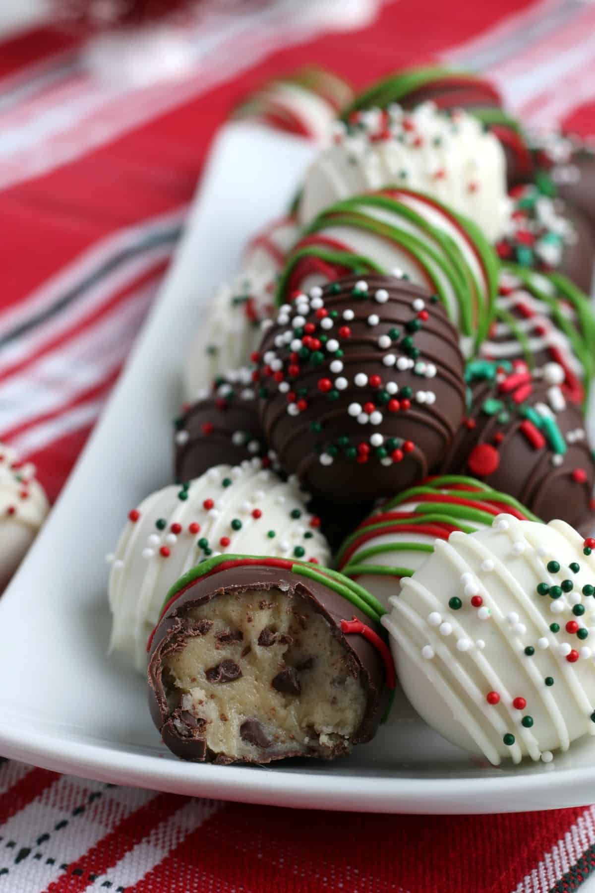Very colorful decorated easy cookie dough balls on a white rectangle plate.