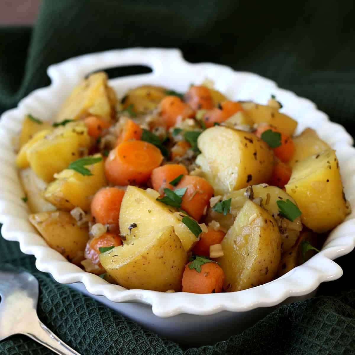 White scalloped bowl filled with potato and carrot chunks for healthy vegan recipes instant pot.