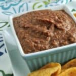 Black bean dip in a square bowl with chips on the side.