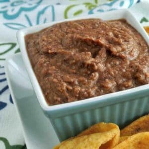 Black bean dip in a square bowl with chips on the side.