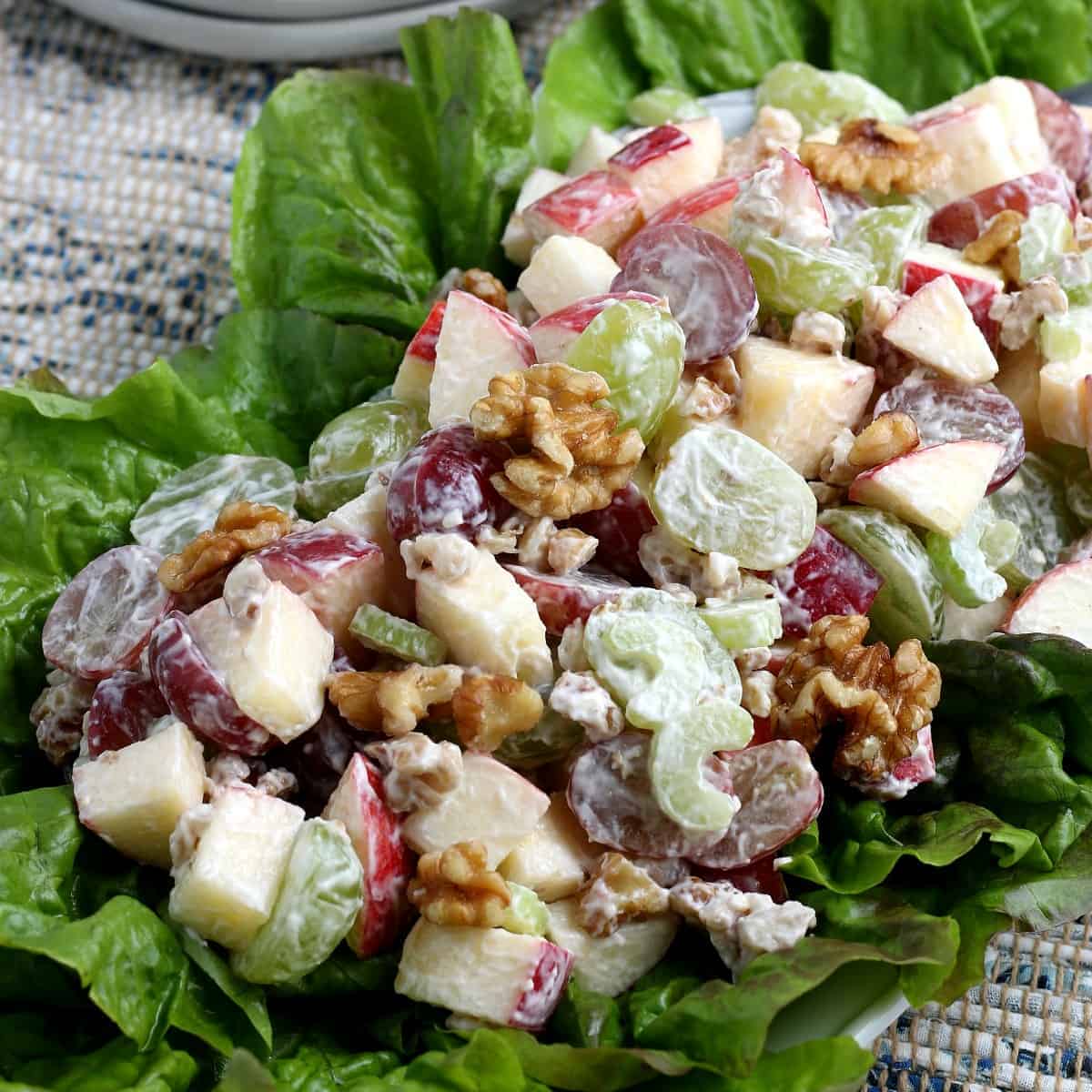 Close up angled view of fresh vegan Waldorf salad on a bed of lettuce.