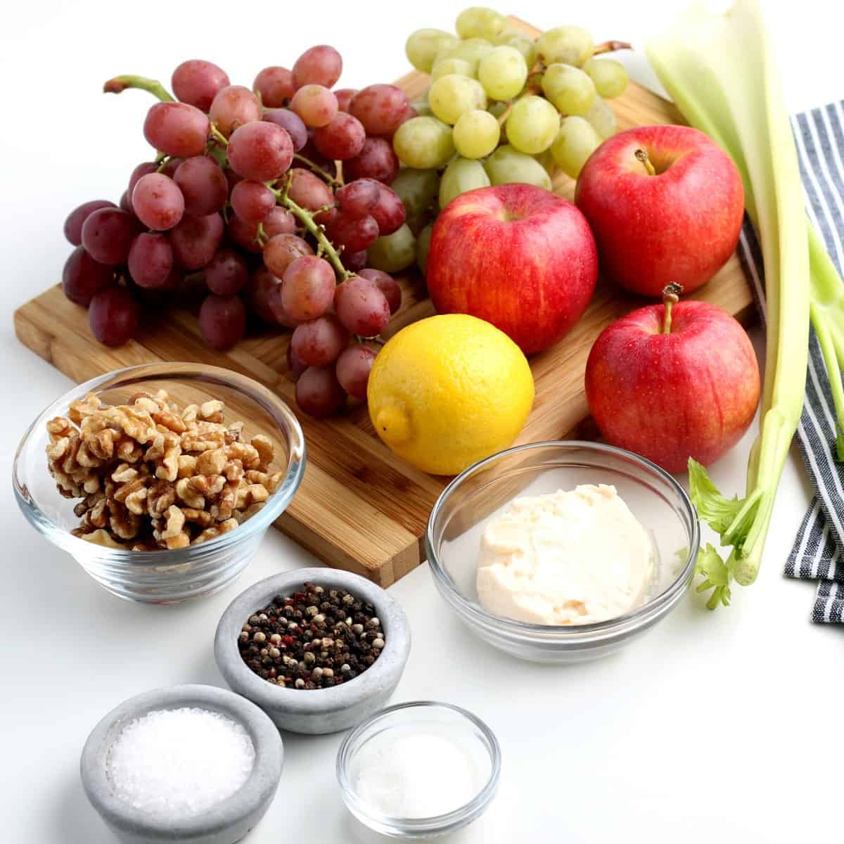 Ingredients for a fresh vegan Waldorf Salad are gathered together on a wooden board.