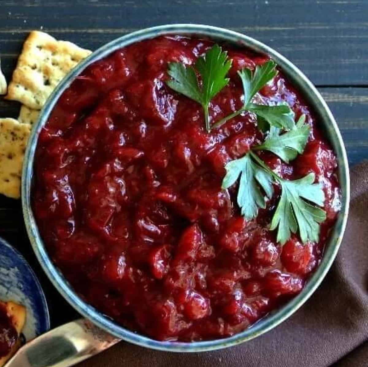 Overhead photos of Cranberry sauce in s blue bowl with crackers.