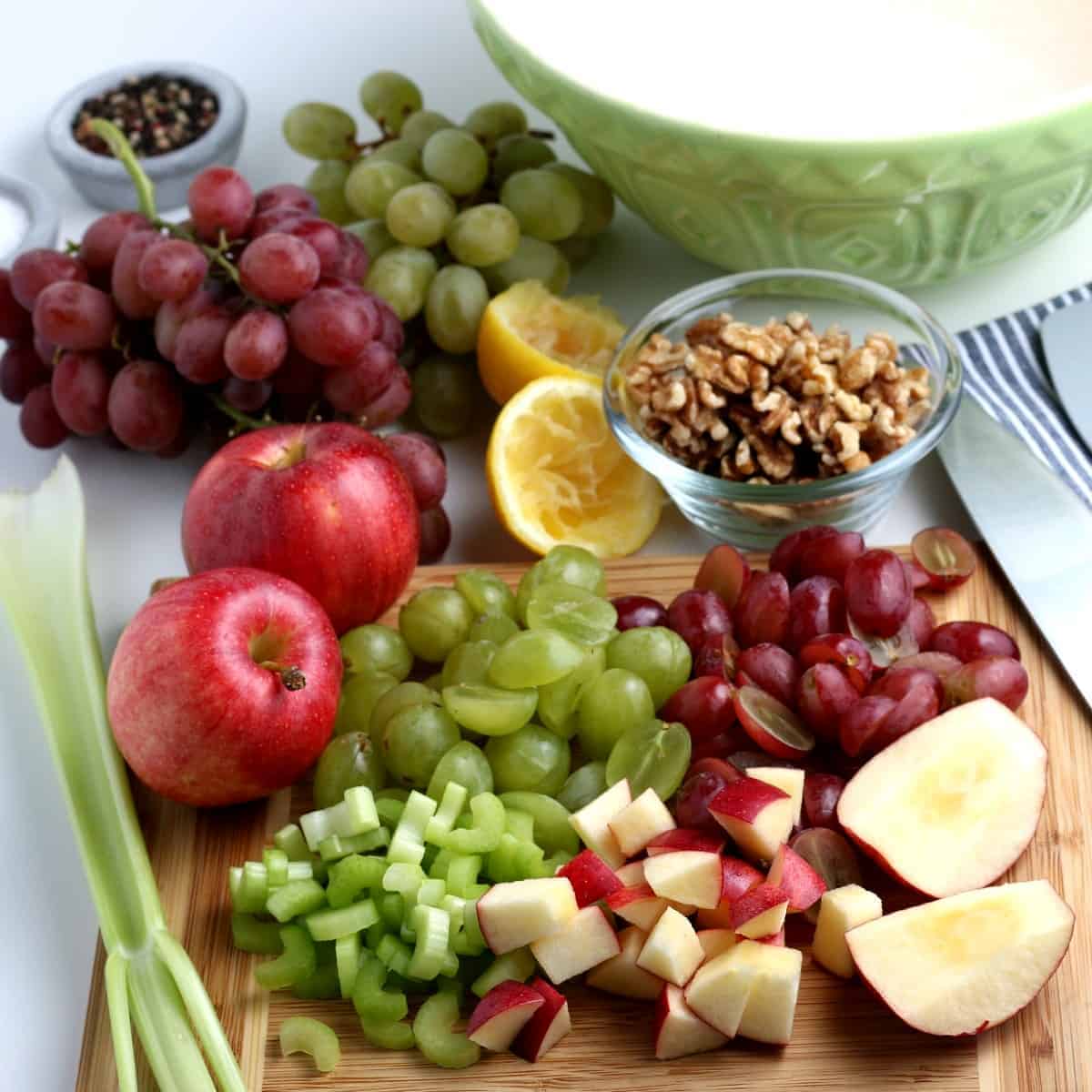 Chopped and sliced fruit and vegetables on a wooden cutting board.