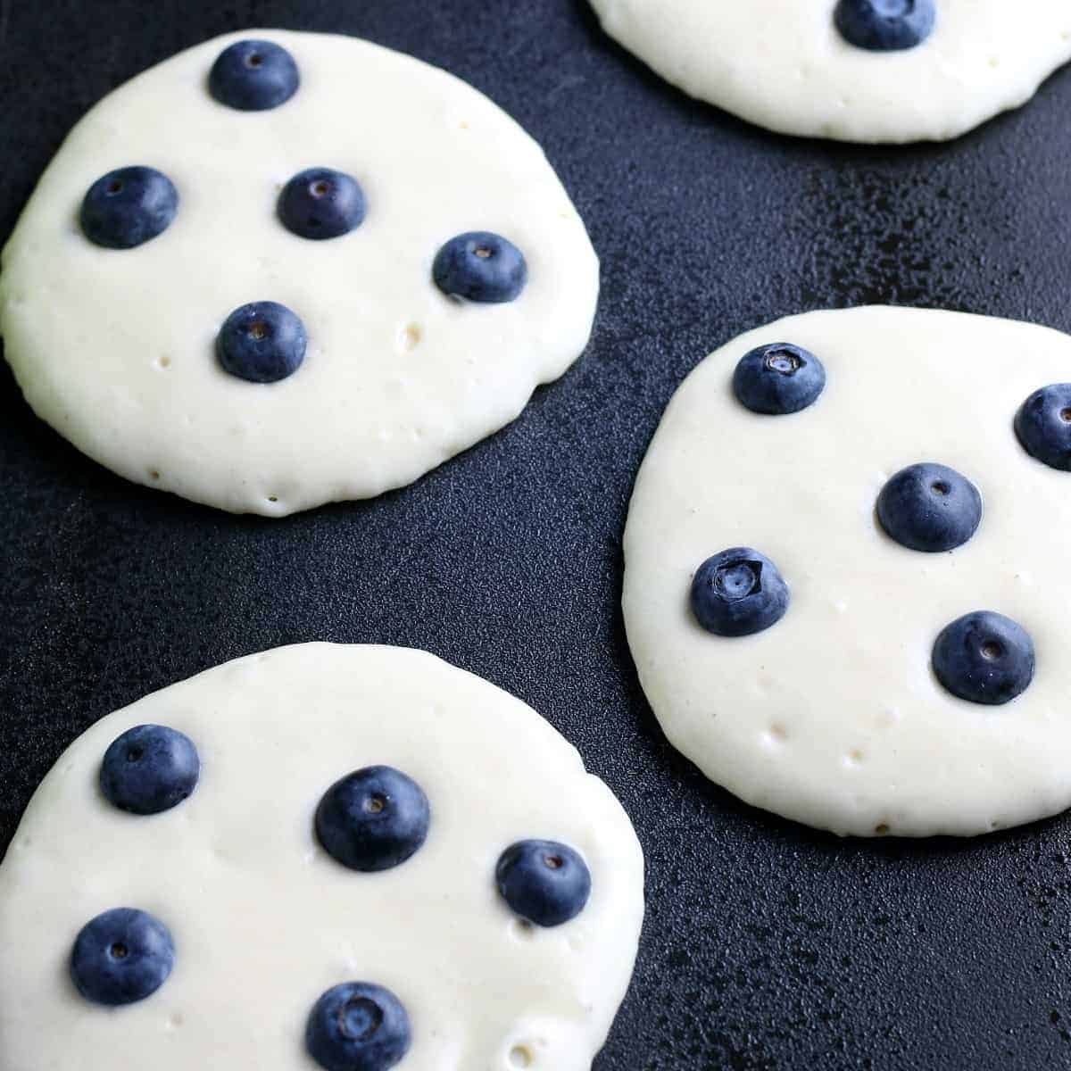 Showing the pancakes fresh on the griddle with the blueberries just added.