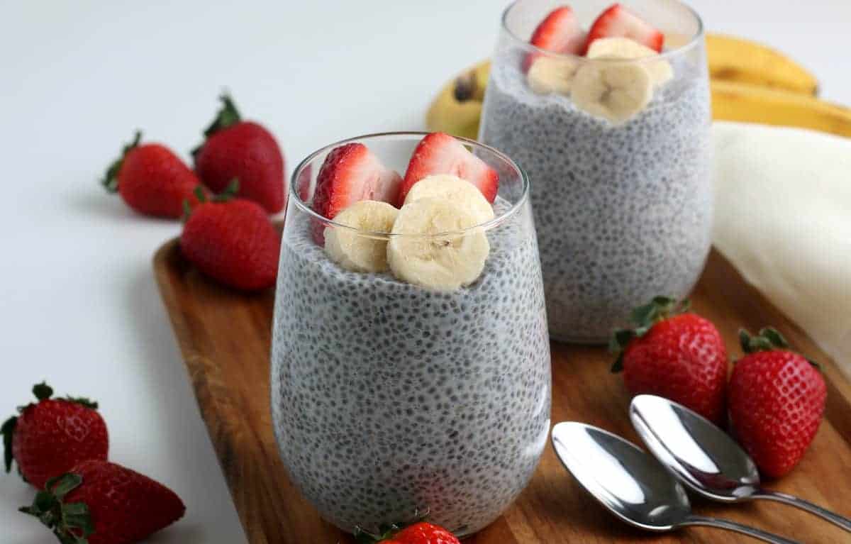 Two glasses filled with a healthy daily meal with strawberries on the side.