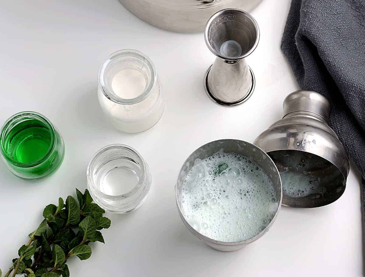 Overhead photo of a lid off of a cocktail shaker showing the green dink inside.