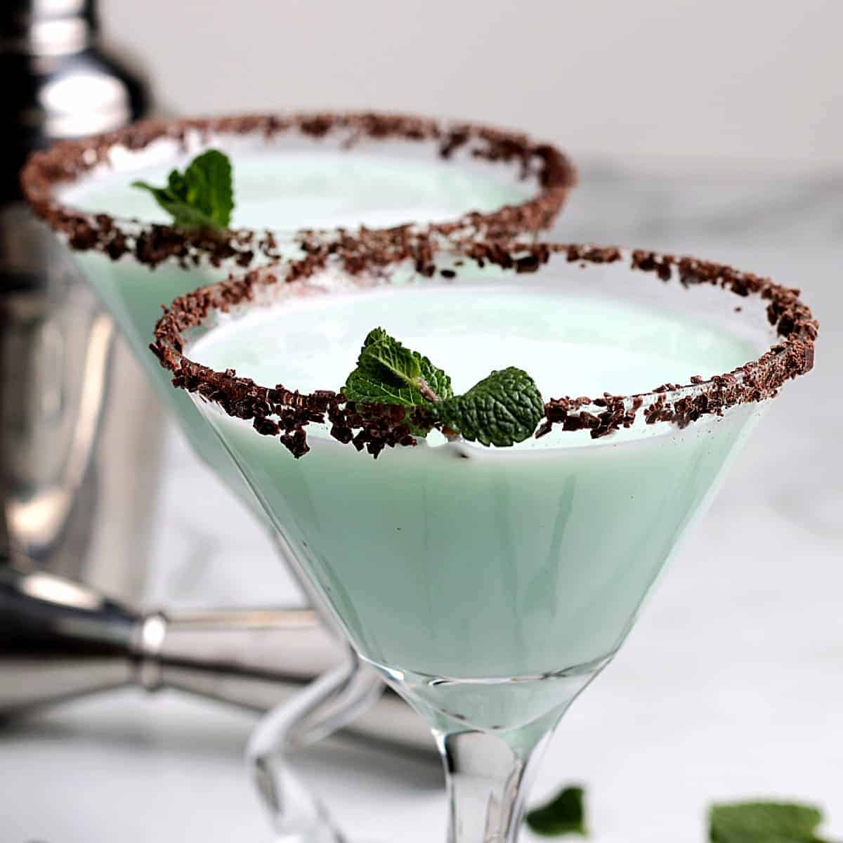 Two stemmed glasses filled with a frothy mint green cocktail