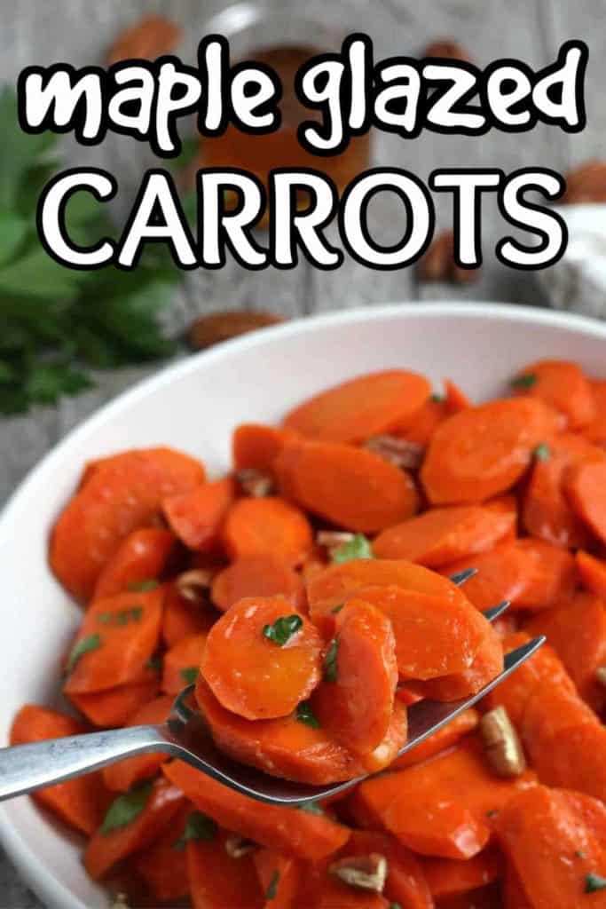Fork full of glazed carrots being held close to the camera lens.
