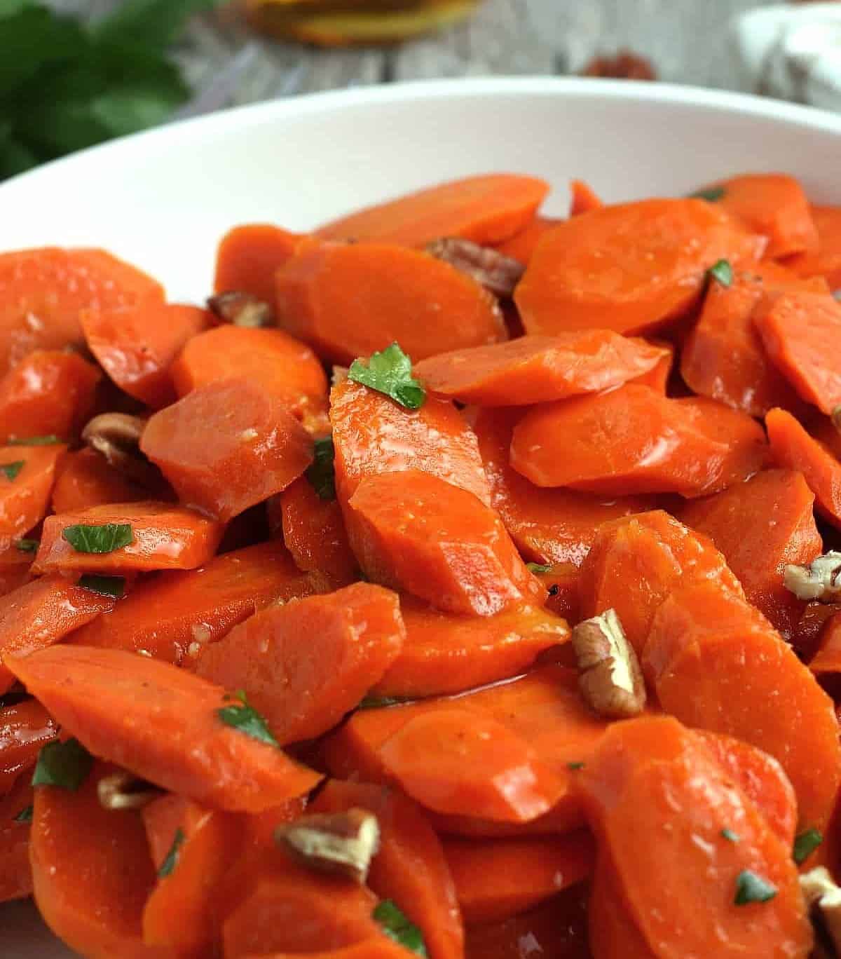 Very close up of cooked sliced carrots with pecans.