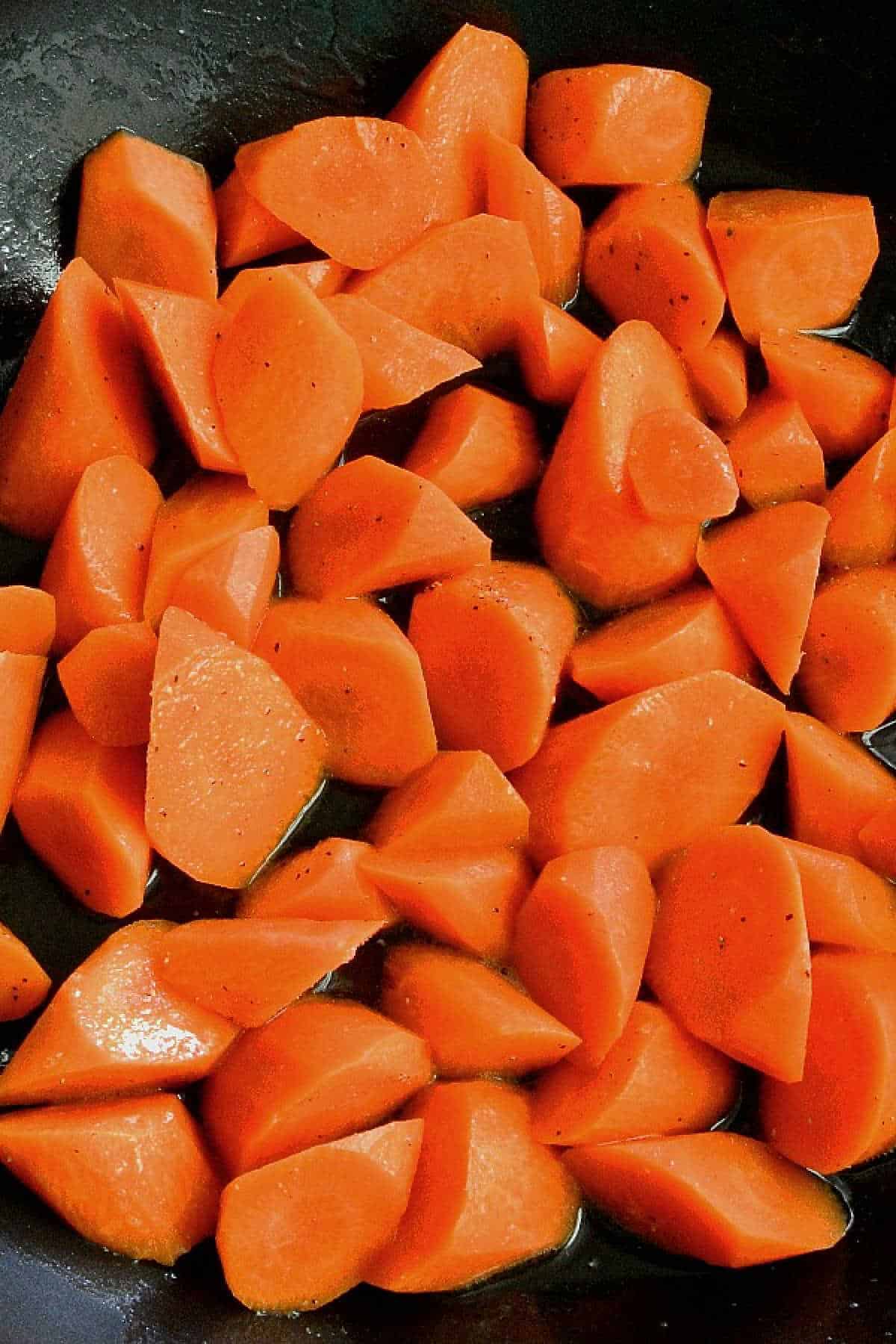 Overhead view of rolled cut carrots in a pan.