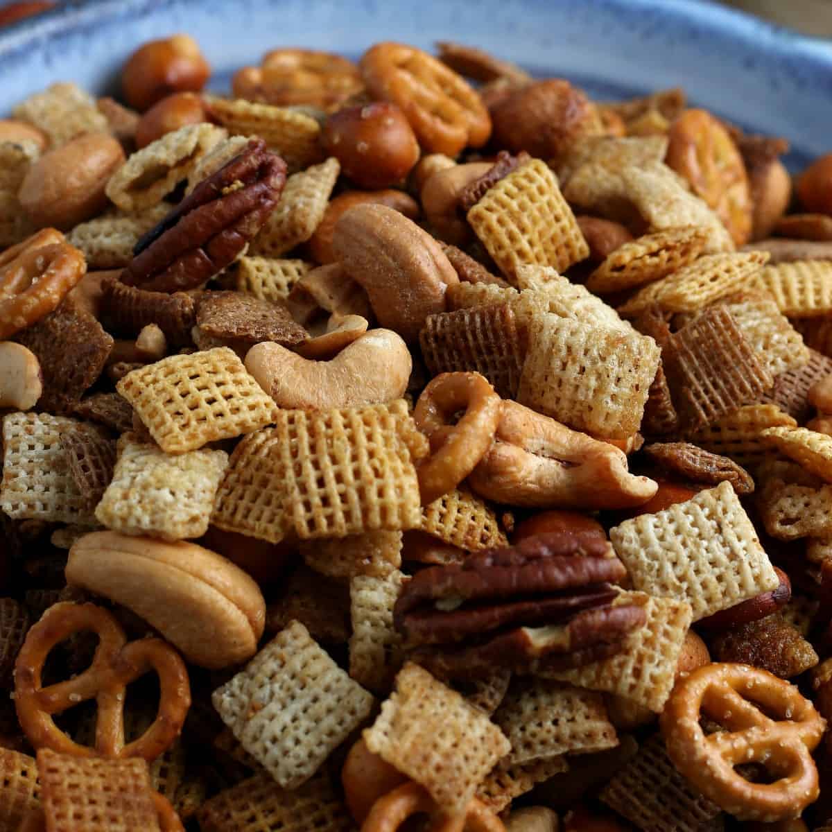 Close up of a snack mix with cereals, pretzels and nuts.