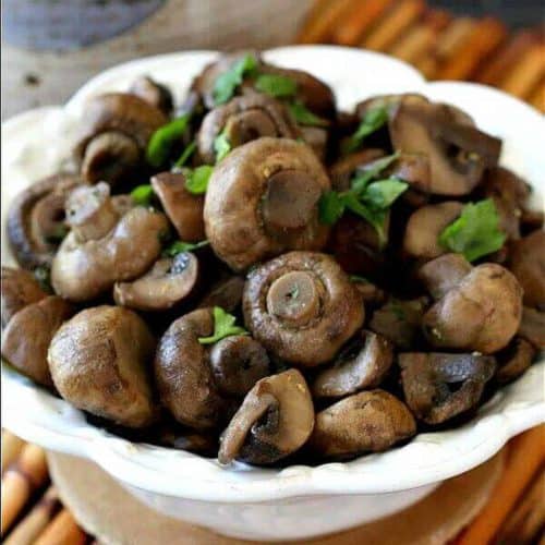 Tilted bowl filled with glistening marinated mushrooms