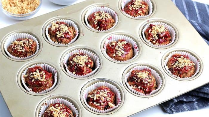 A muffin tin full of baked muffins with a jelly syrup topping.