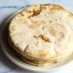 Stack of 4 golden baked pita bread rounds on a white plate.