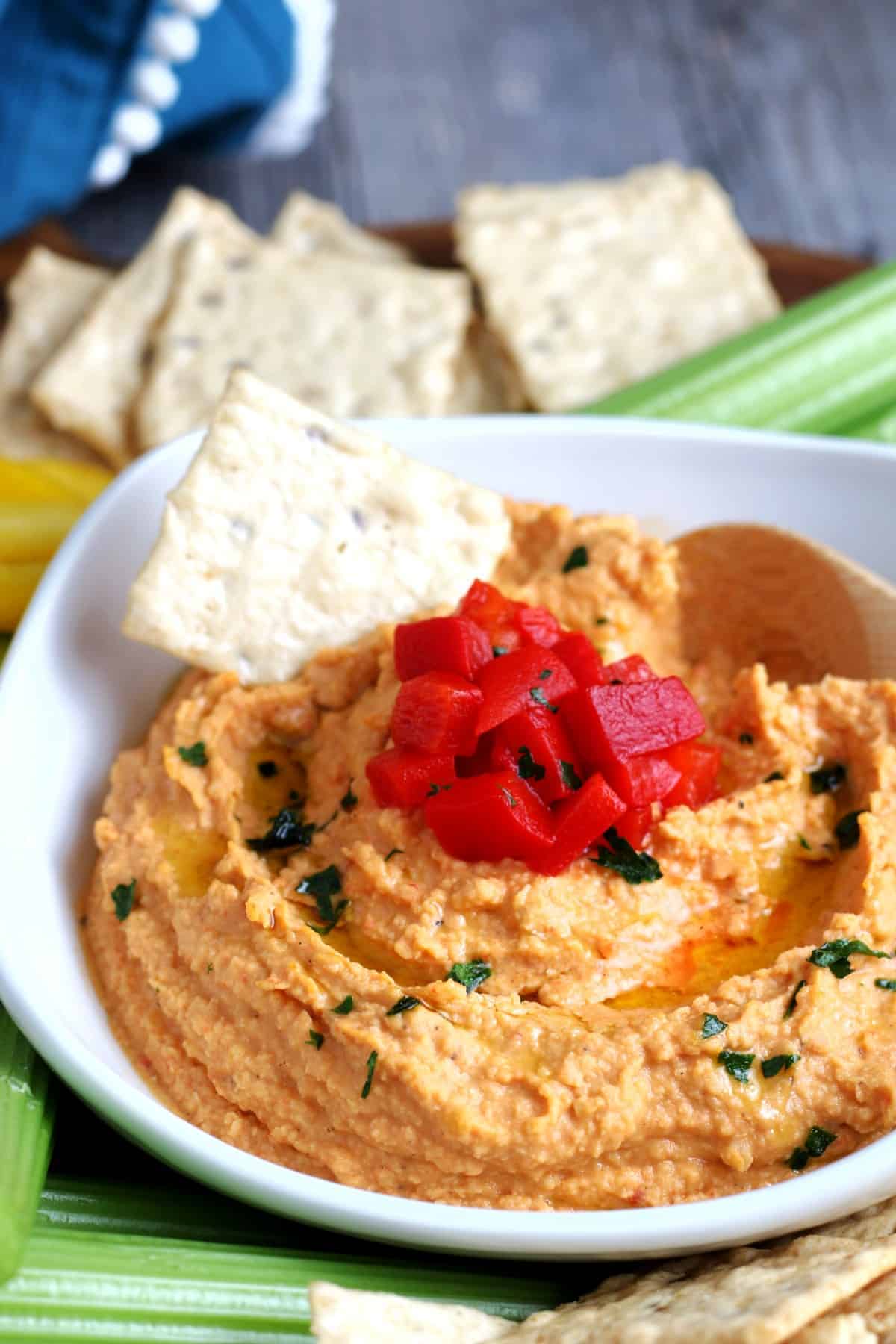 Extreme closeup photo of red bell hummus swirled with an olive oil drizzle.