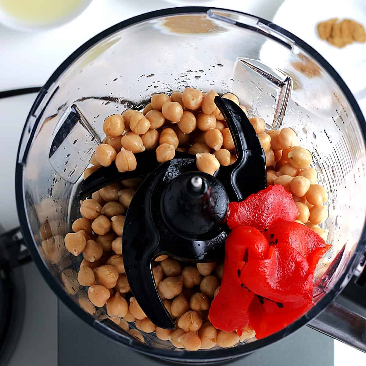 Overhead of chickpeas and red bell peppers in a food processor.