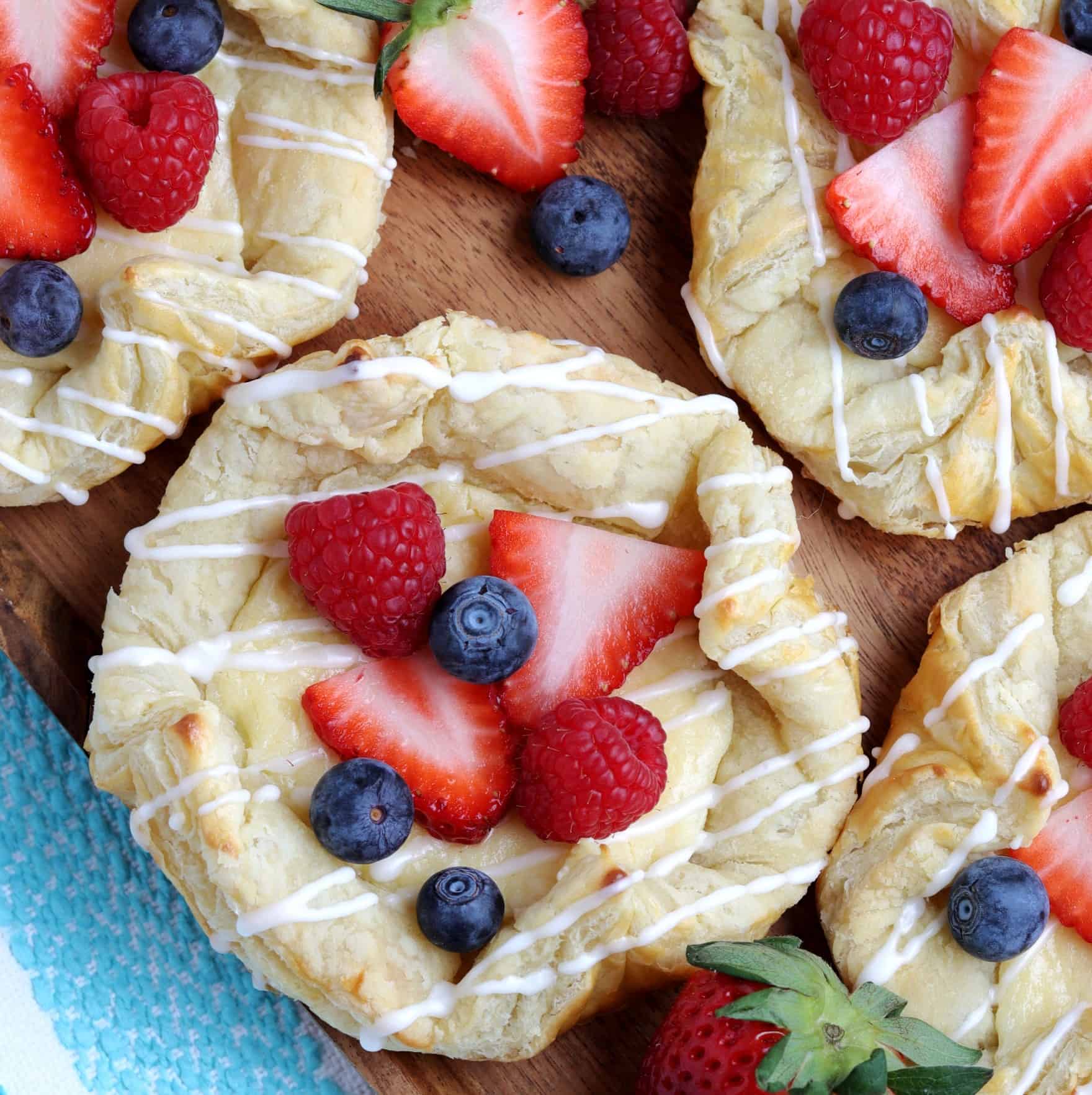 Centered Vegan Cream Cheese Danish drizzled with icing and berries.