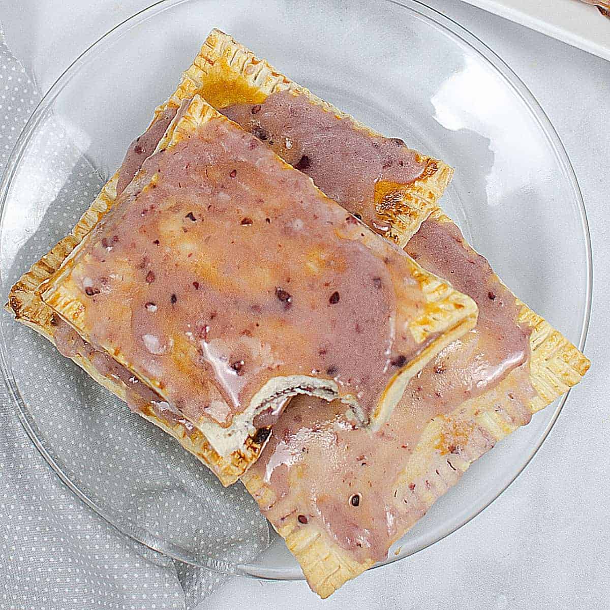 Overhead view of three iced pop tarts on a glass plate.