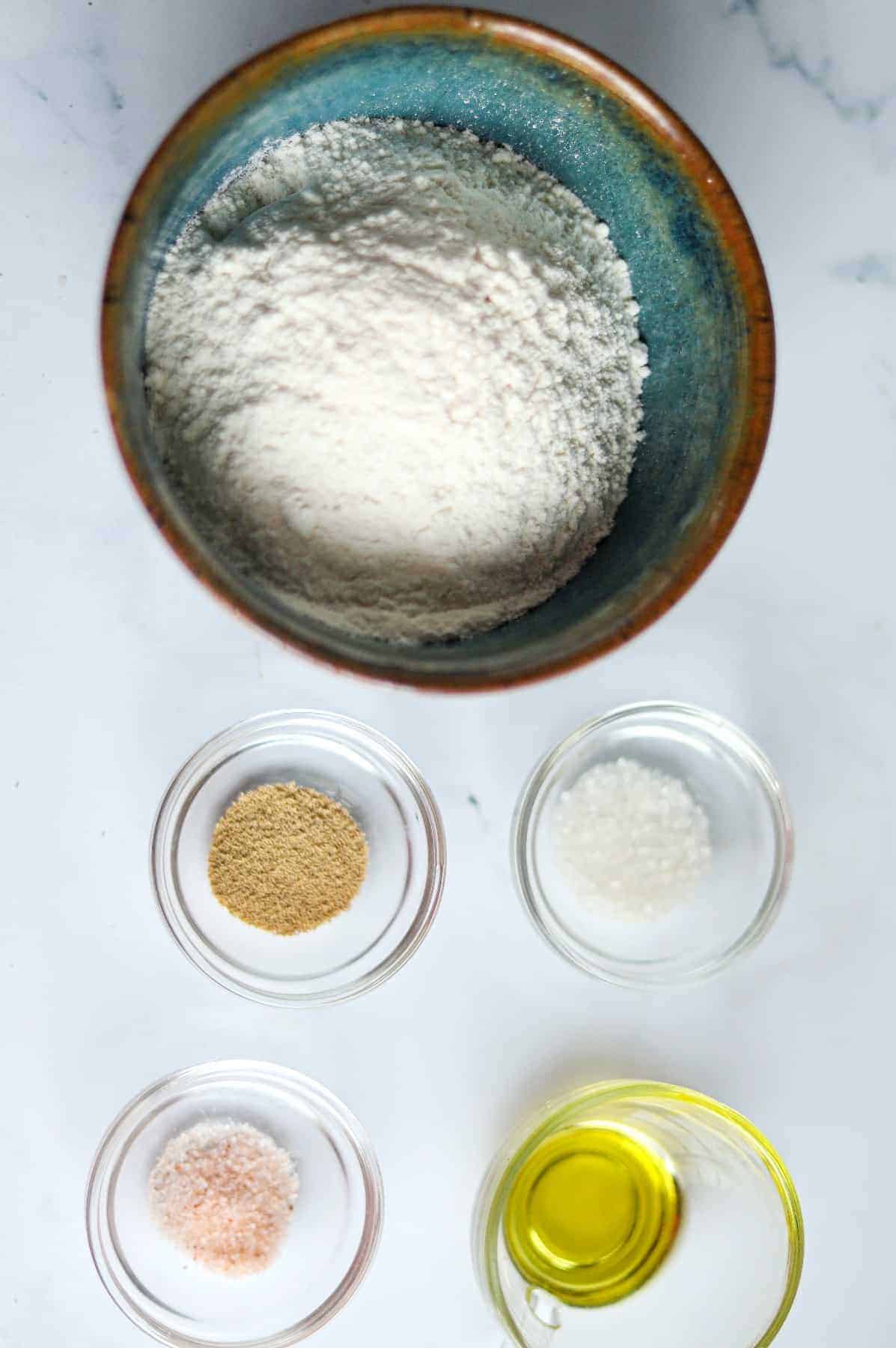 Small bowls holding the ingredients to make pita bread.
