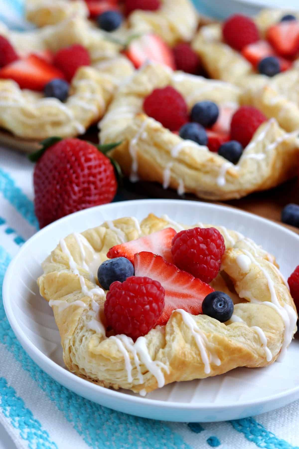 Centered breakfast treat has berries in the center with more pastries behind.