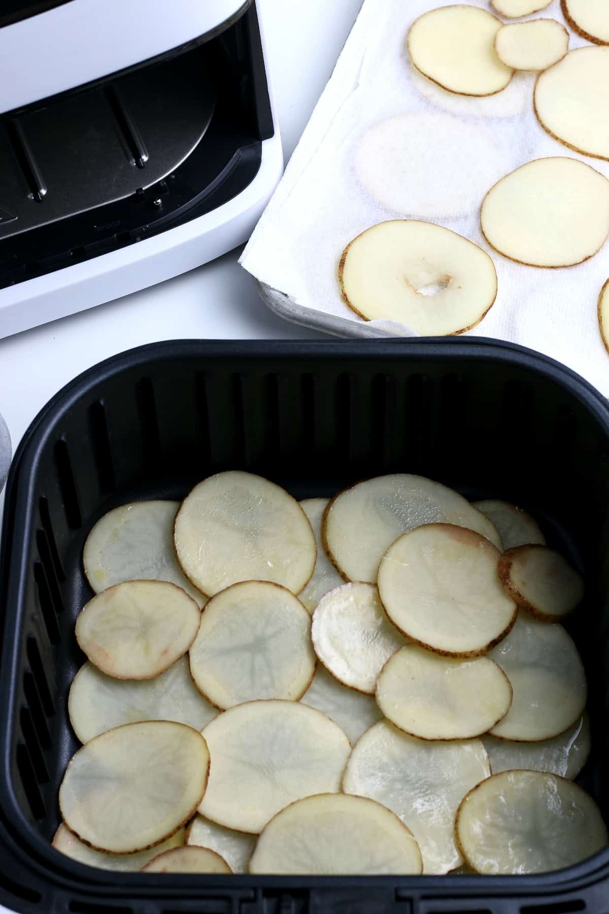 Layered sliced potatoes in an air fryer.