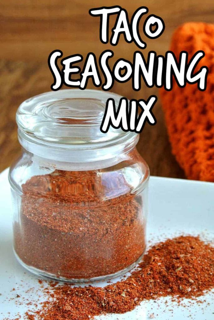 Glass jar is filled with rich colored taco seasoning mix.