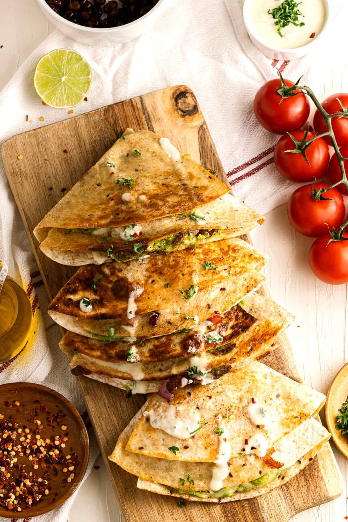 Overlapping folded and cooked tortilla sandwiches with vegan crema.