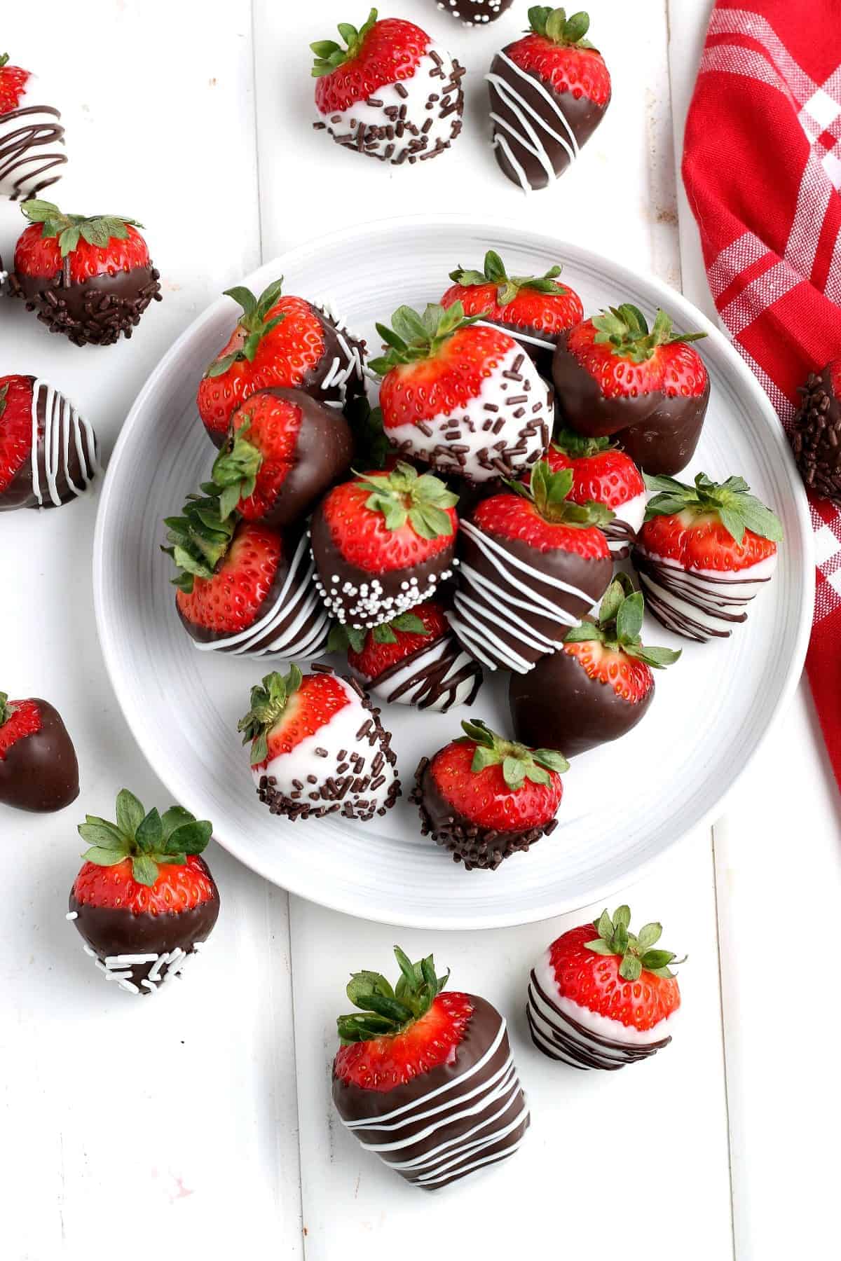 Overhead photos of chocolate strawberries on a white plate and scattered around.