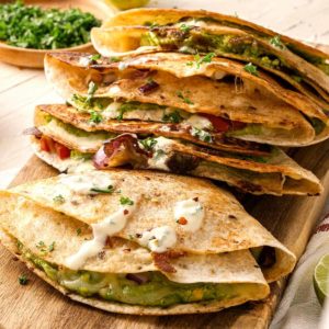 Four folded vegetarian quesadillas overlapping each other on a cutting board.