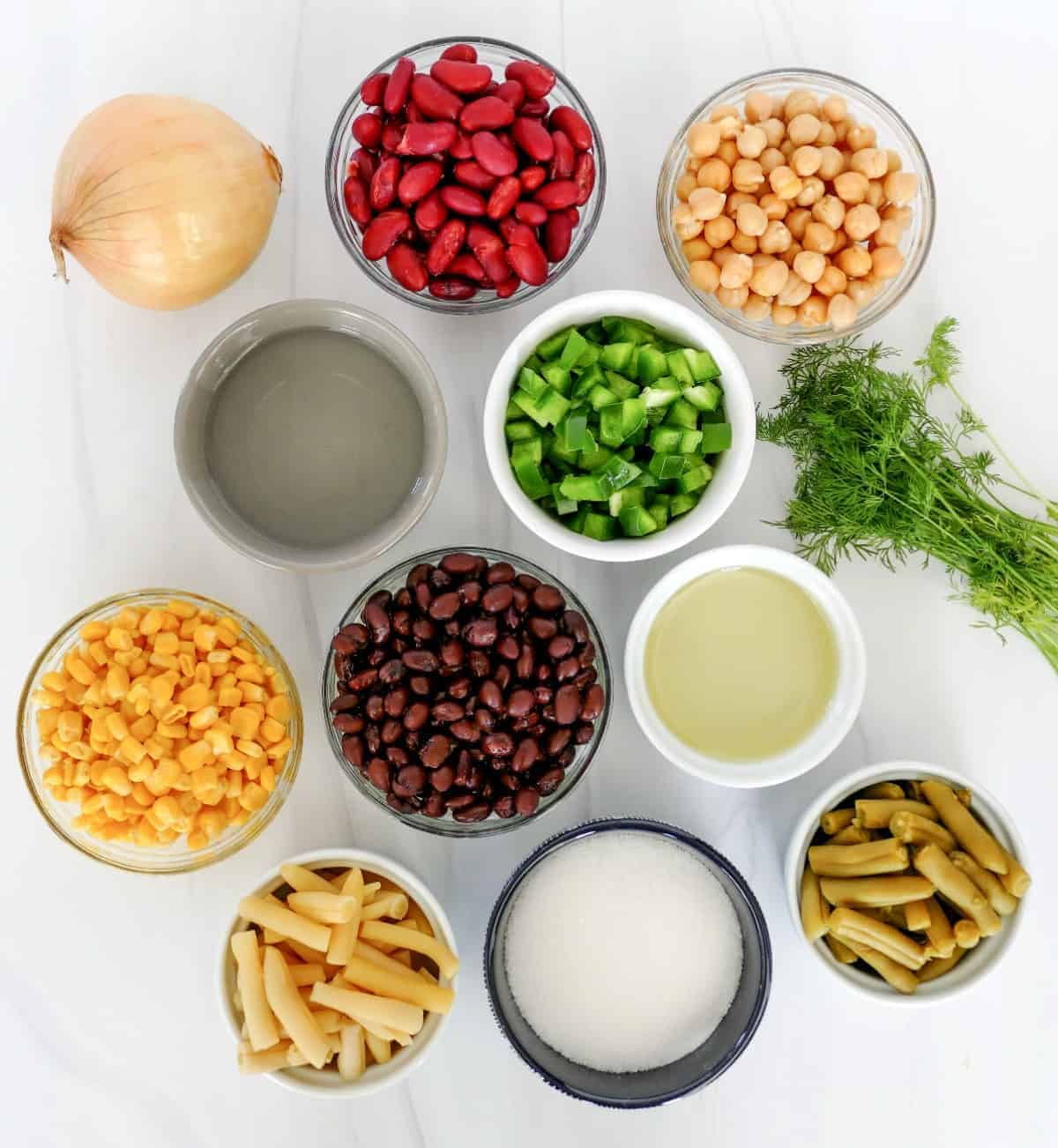 All of the ingredients for a five bean salad in individual bowls.