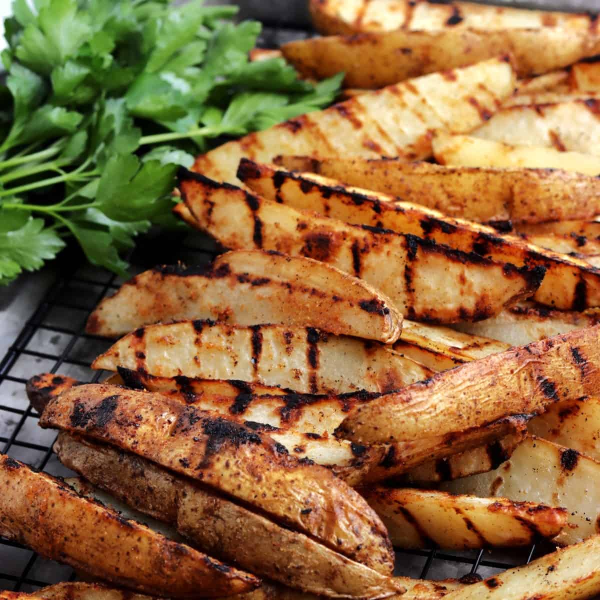 Close up of summertime veggies on a black rack with fresh parsley.