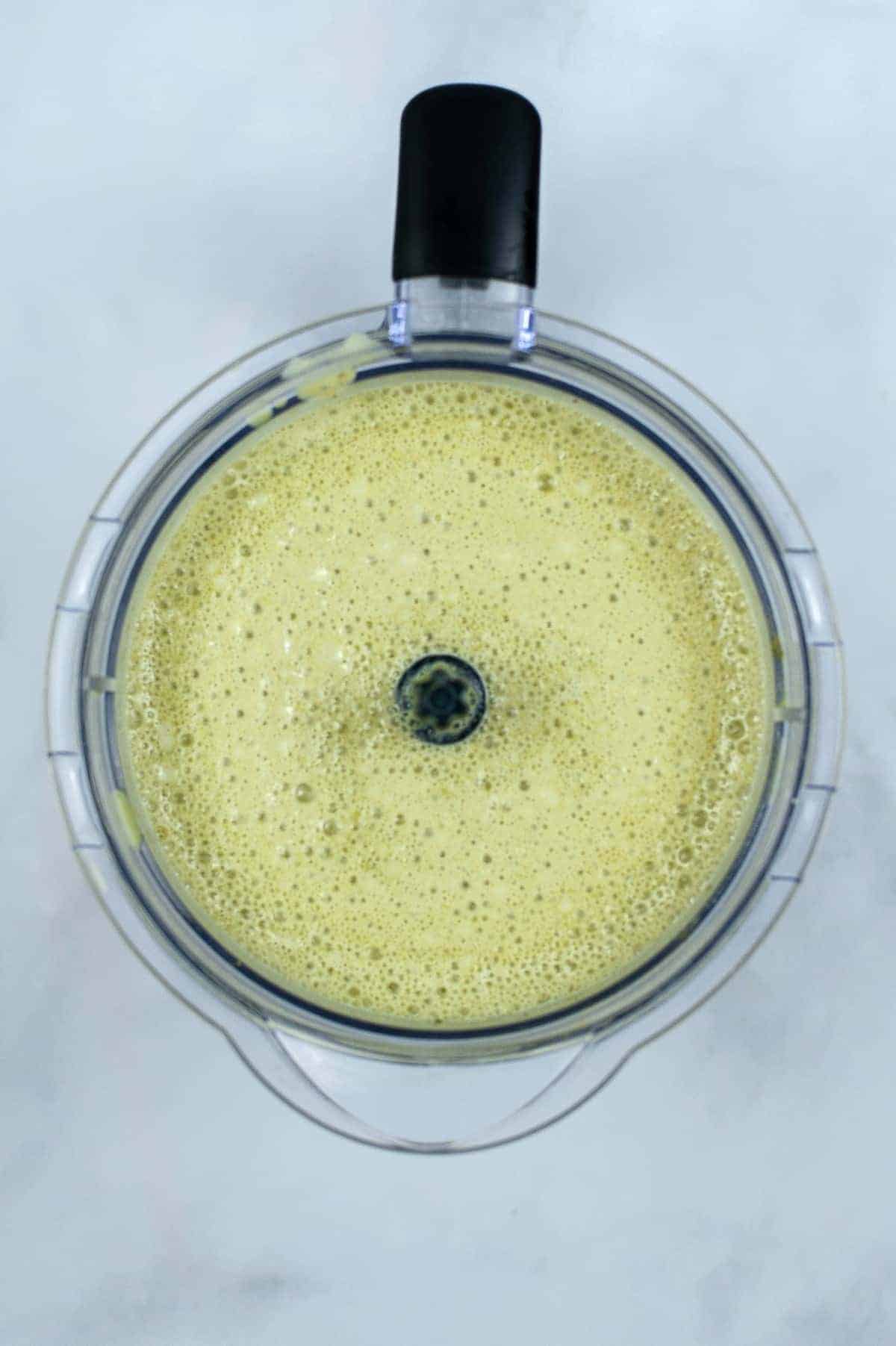 Overhead of blended and foamy matcha green tea in a blender.