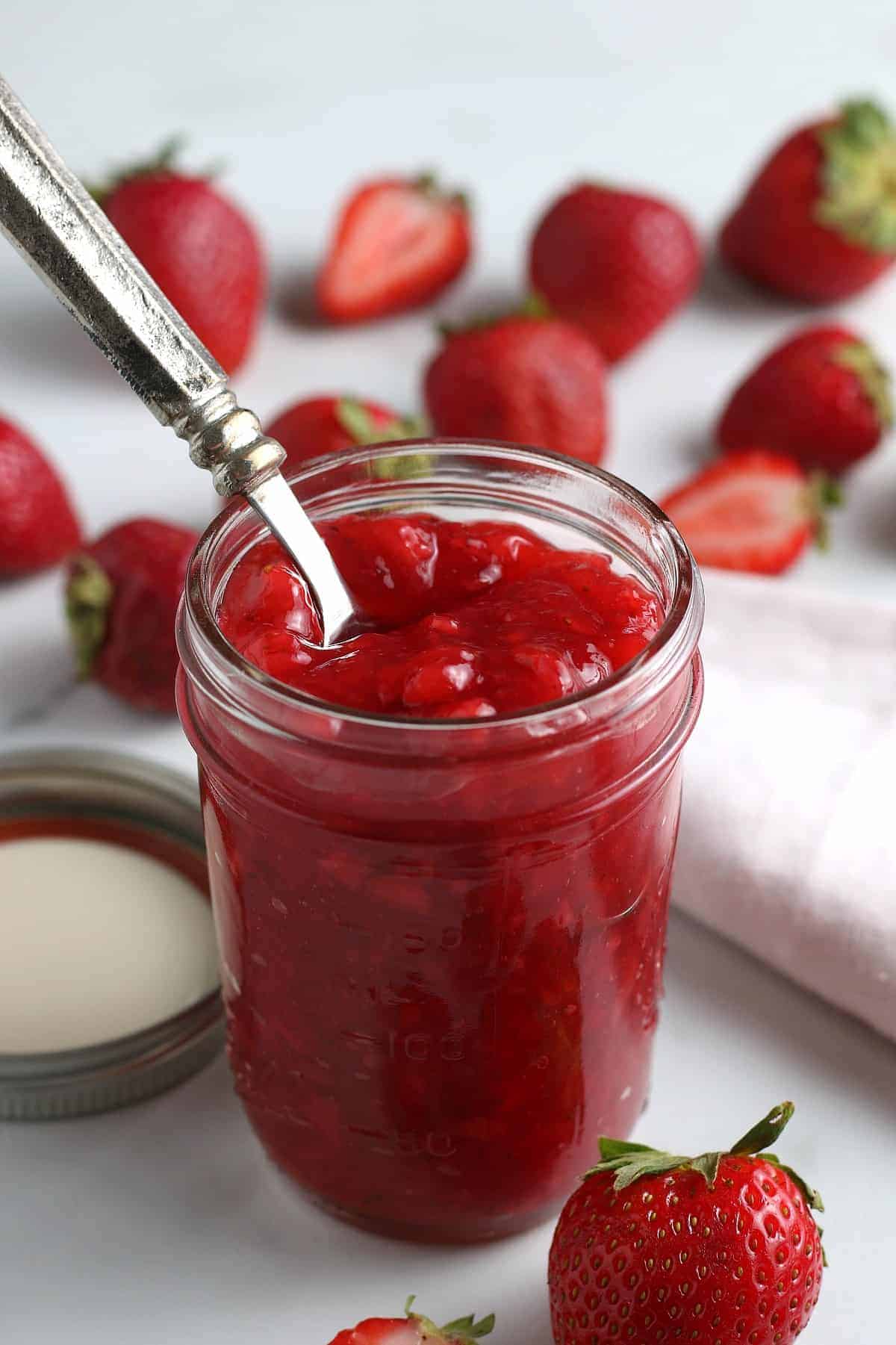 Strawberry sauce bring scooped out of a canning jar.