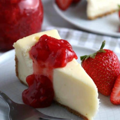 Slice of cheesecake with strawberry sauce poured over the top.