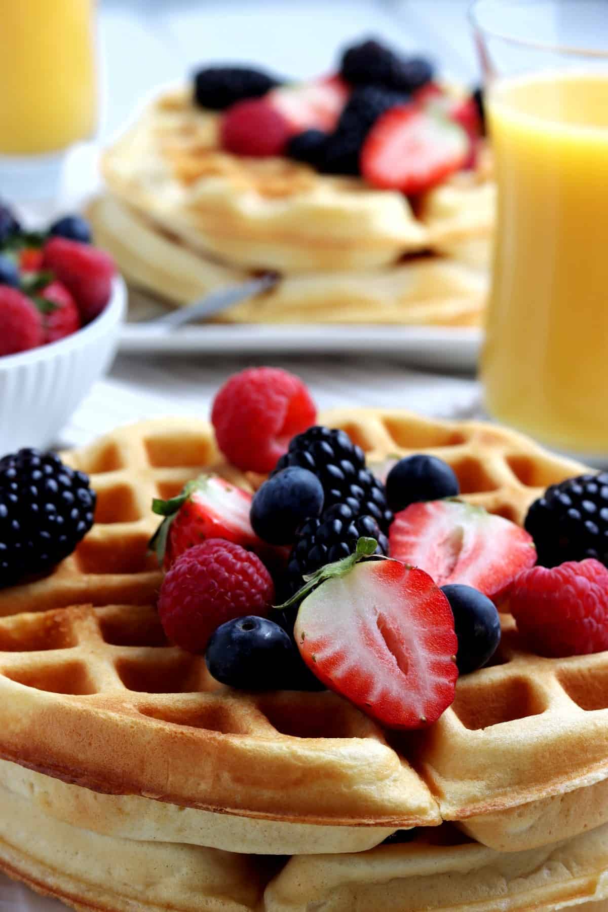 Close up of breakfast with berries and orange juice behind.