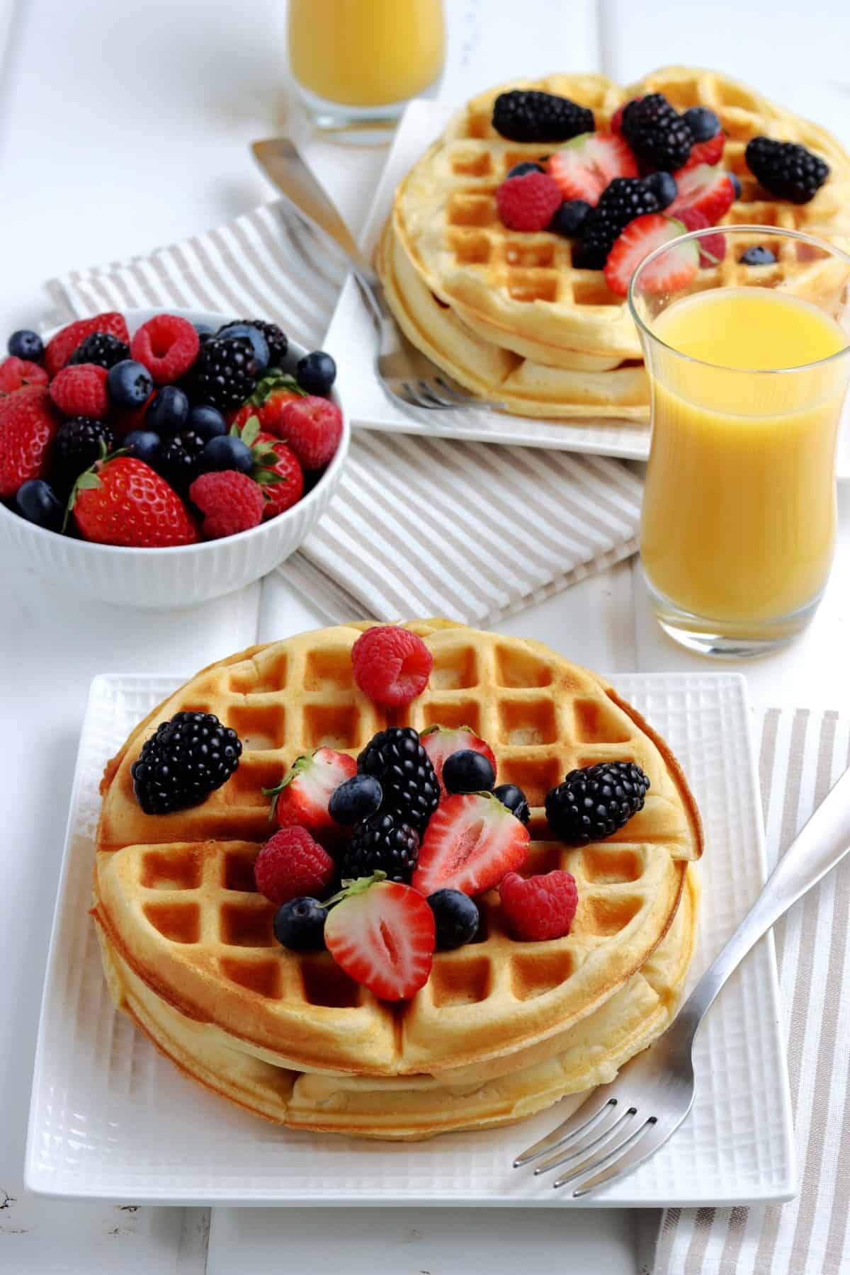 Full setting at the table with homemade waffles recipe, oj, berries and syrup.