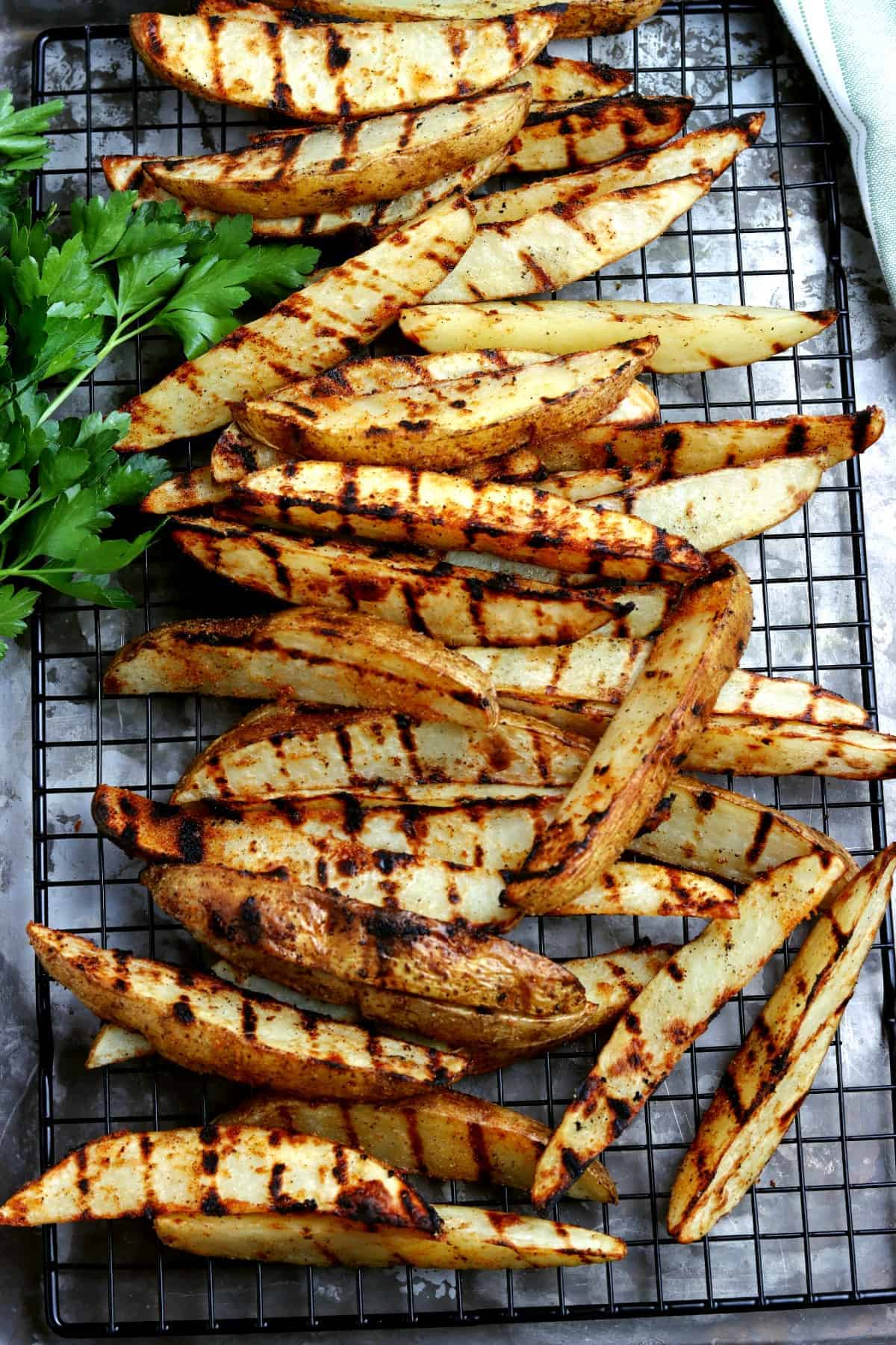 Overhead view of grilled potato wedges side dish on a rack.