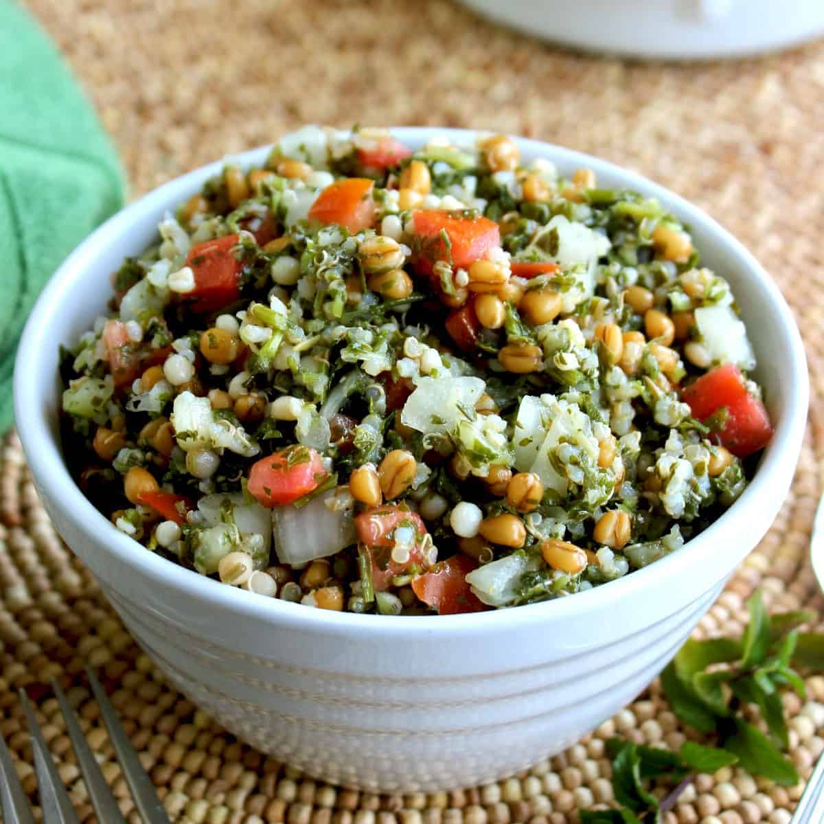 Titled bowl filled with tabouli salad on a beaded mat.