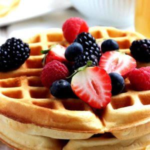 Close up of stacked waffles with fresh fruit on top.